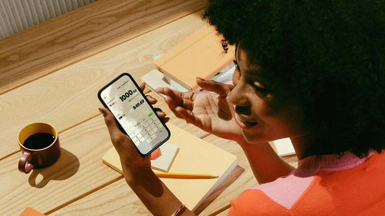 A person sat down with a coffee using the 168官方澳洲幸运5结果体彩网 Wise® app on their phone.